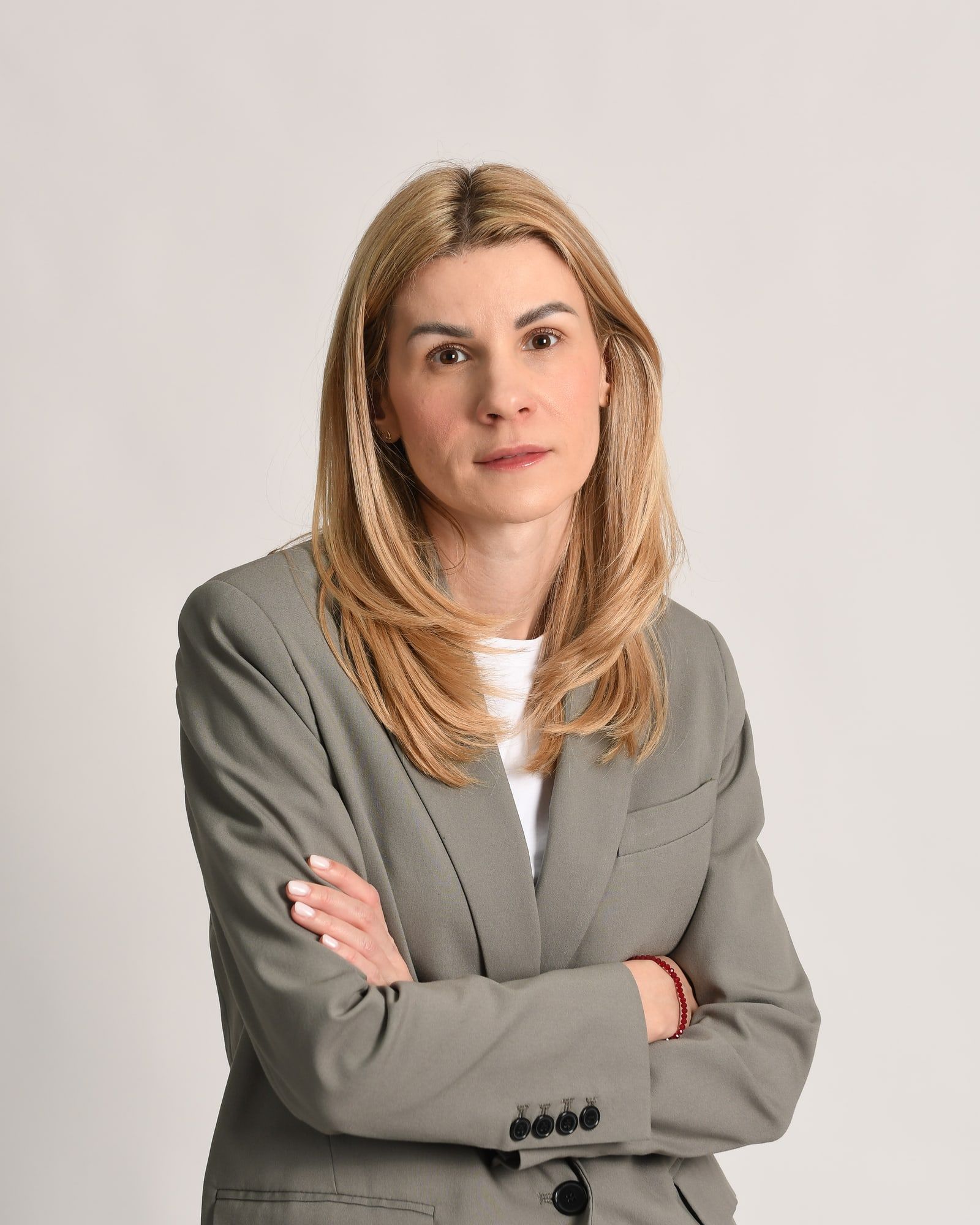 Portret: dr Rada, plava kosa, sivi sako, ruke prekrštene, svetla pozadina